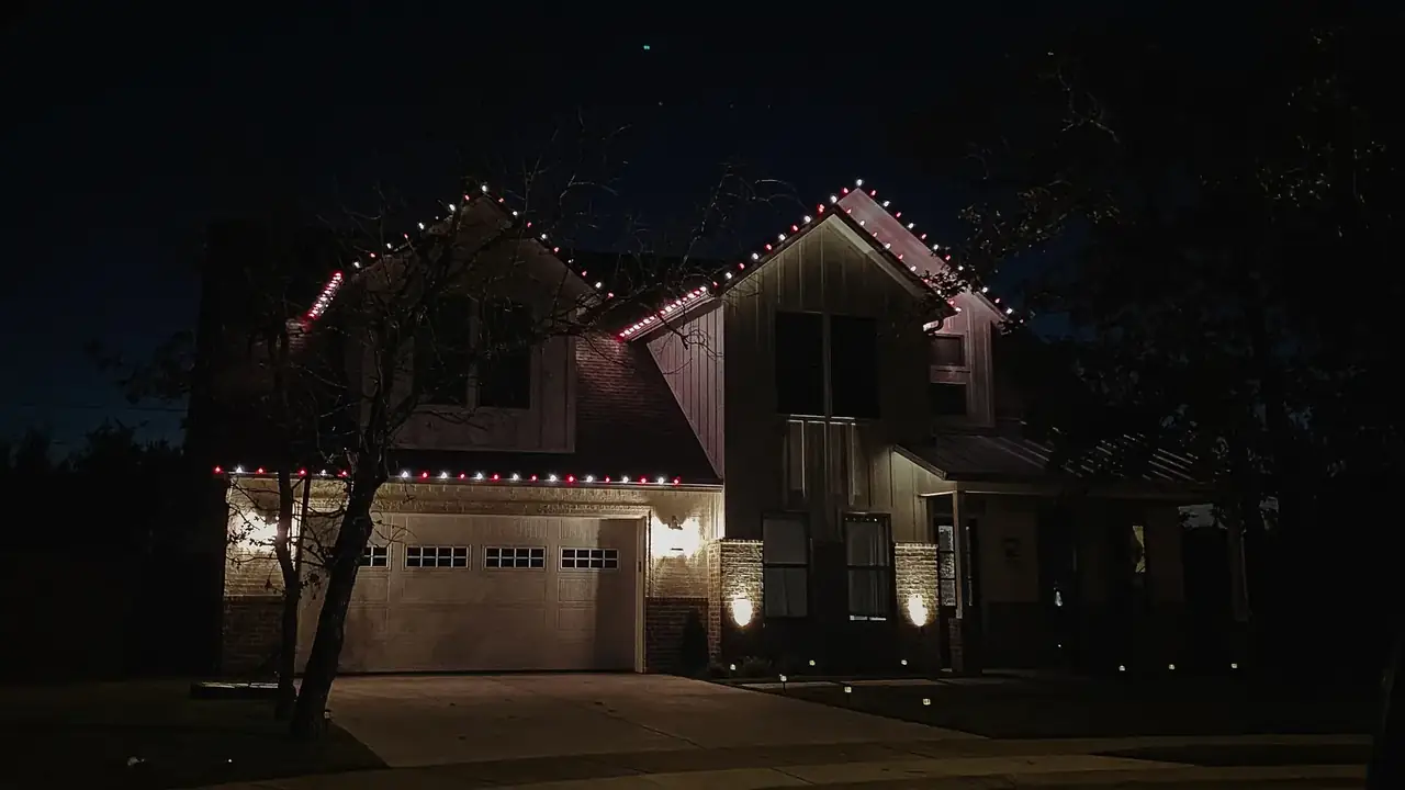 Christmas lights outlining the roofline and dormers of a custom home